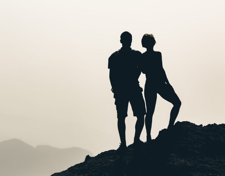 Couple celebrating, reaching life goal and love, business concept with man and woman looking at view. Motivational and inspirational silhouette landscape.